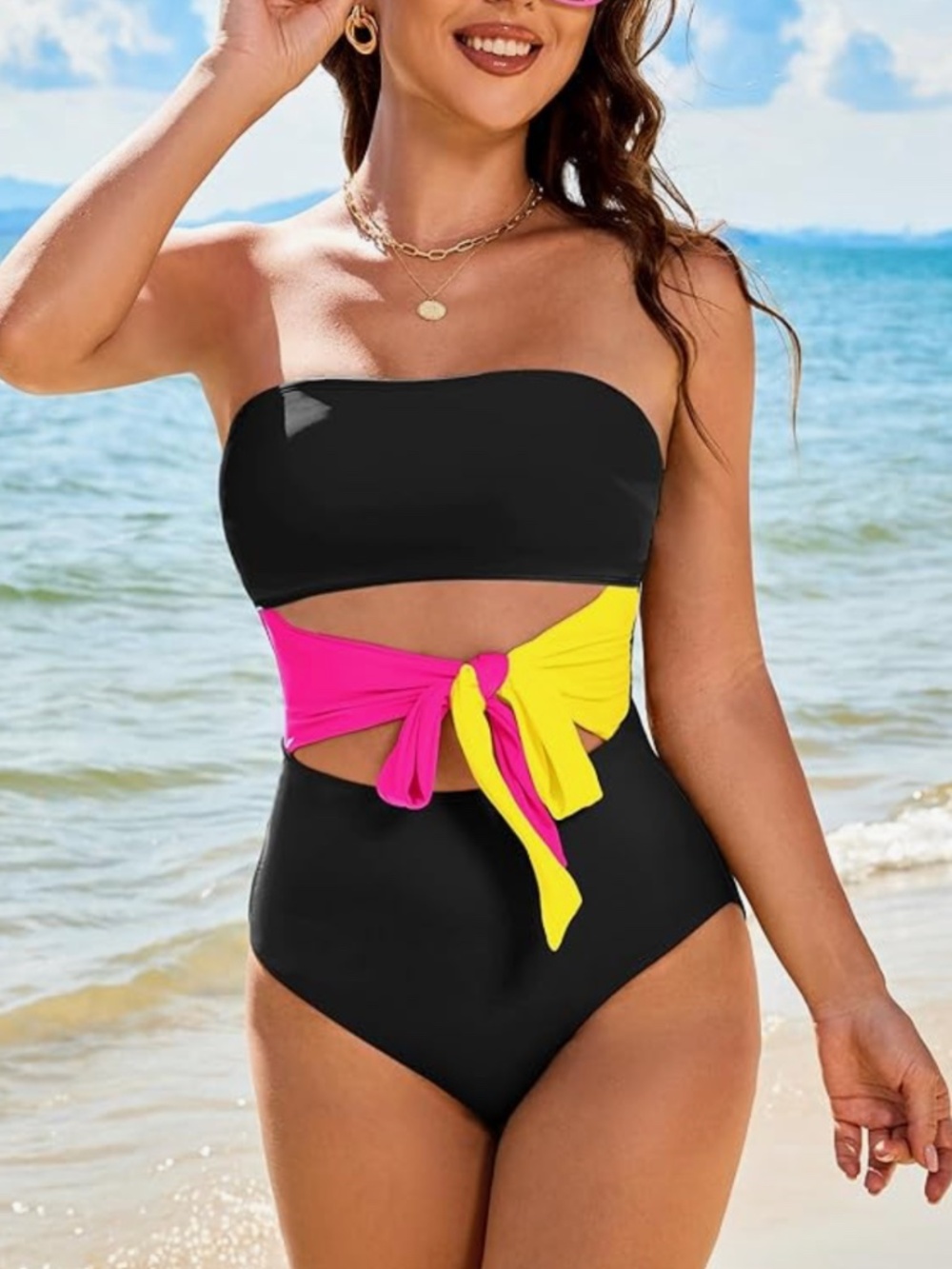Stylish black one-piece swimsuit with a vibrant pink and yellow tie detail at th